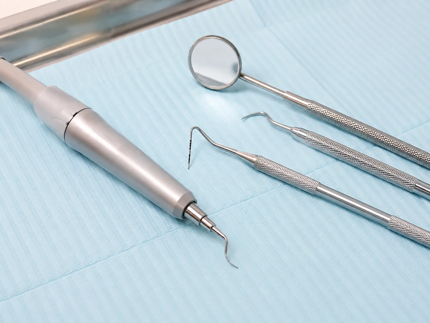 AI-generated explanatory image of an ultrasonic scaler and periodontal instruments, not the clinic's equipment